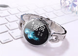 Silver smartwatch on a white keyboard with a blurred gemstone in the corner