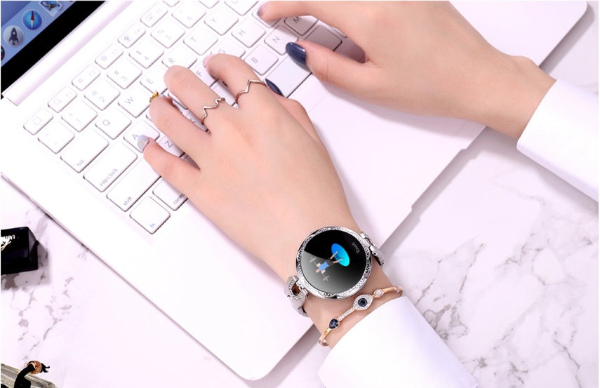 Smartwatch on a wrist with a laptop in the background